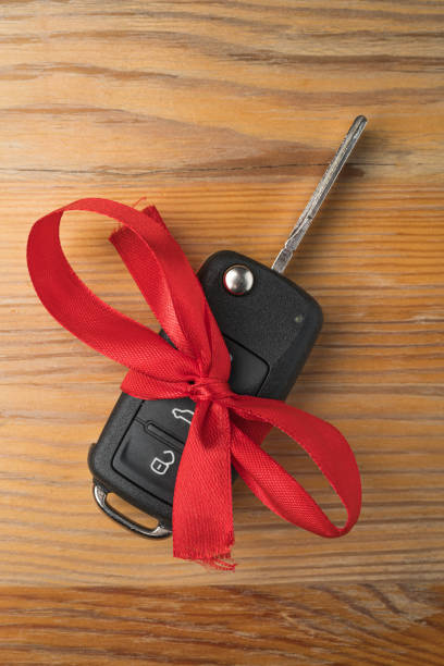 istock Car key with red bow on natural wooden table background. 1194650606