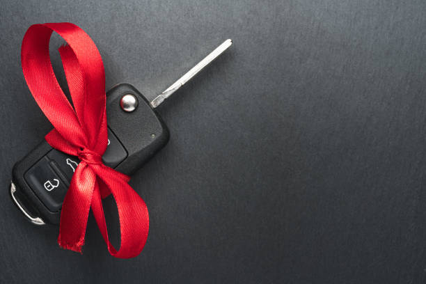istock Car key with red bow on dark black slate plate. 1194650625