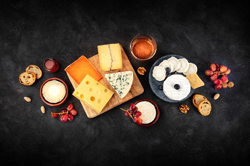 Cheese platter with wine and fruit, a flat lay overhead shot on a black background with copy space