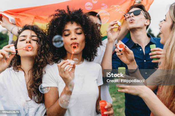 Friends Having Fun With Soap Bubbles Together At The Park Stock Photo - Download Image Now