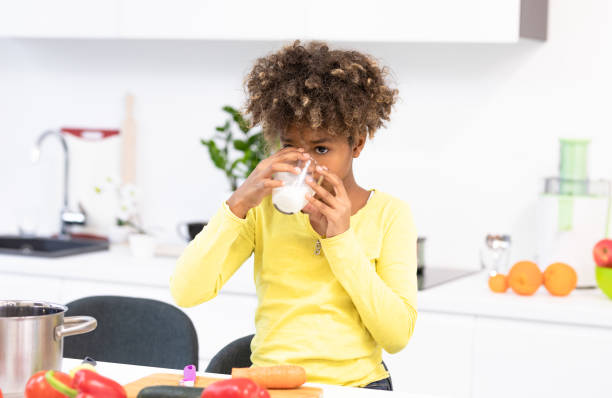 istock beautiful afro child preparing a meal and drinking milk in a white kitchen 1194654054