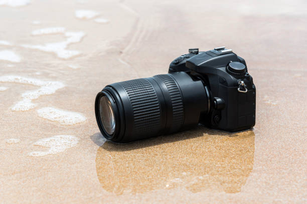 istock DSLR camera on beach wet from water sea wave 1194658142