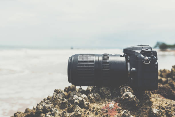 istock DSLR camera on stone beach wet from water sea wave 1194658162