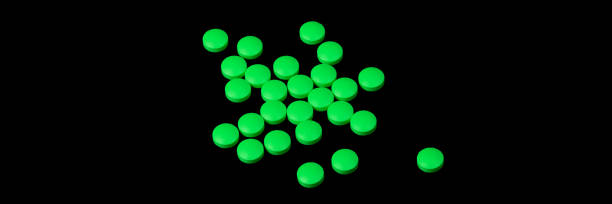 istock Green pills are scattered on a black background. 1194662314