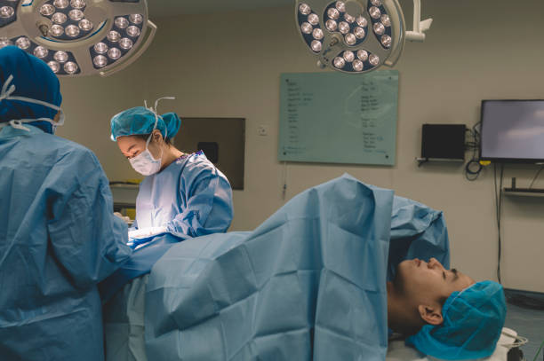 a group of surgeon and nurses operating on a chinese male patient's leg in operating room a group of surgeon and nurses operating on a chinese male patient's leg in operating room surgical light stock pictures, royalty-free photos & images