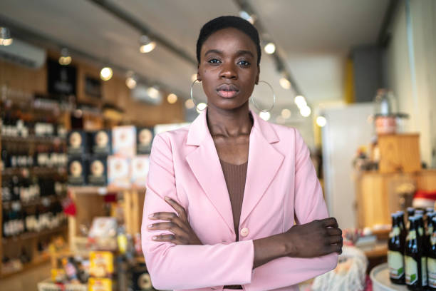 ritratto di una donna d'affari/ imprenditore serio in piedi con le braccia incrociate in un mercato - owner small business restaurant african ethnicity foto e immagini stock
