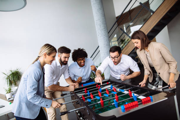istock Happy young office workers playing table football 1194665200