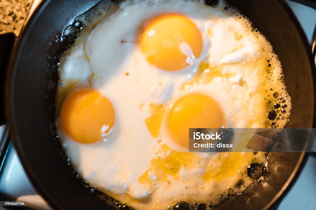 Egg omelette is being prepaired in a frying pan close up - Three yellow eggs in Eastern Europe Latvia Riga Egg omelette is being prepaired in a frying pan close up - Three yellow eggs in Eastern Europe Latvia Riga. Appetizer Stock Photo