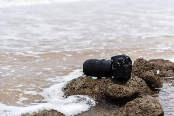 istock DSLR camera on stone beach wet from water sea wave 1194665760