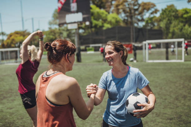 Female soccer players shaking hands before match Group of women, female soccer players together outdoors on soccer field, two women shaking hands. football player girlfriend stock pictures, royalty-free photos & images