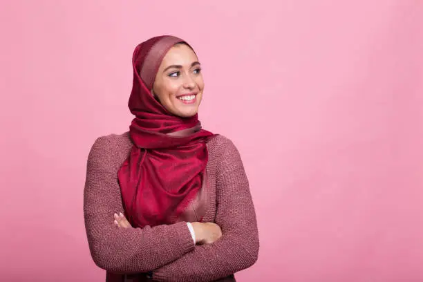 Young woman standing in front pink background