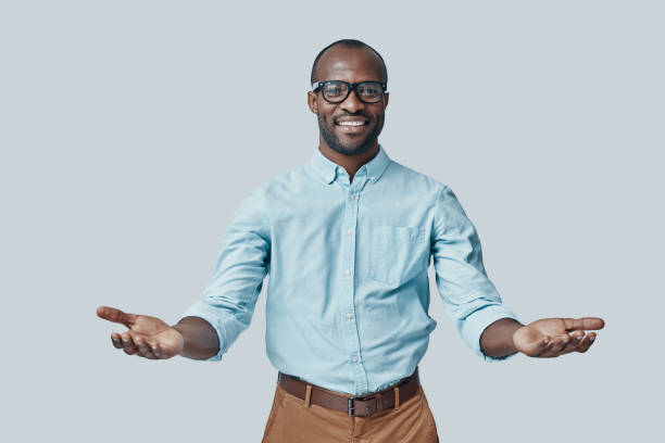 Handsome young African man Handsome young African man keeping arms outstretched and smiling while standing against grey background arms outstretched stock pictures, royalty-free photos & images