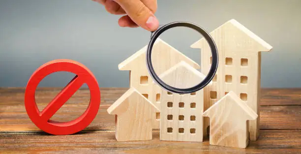 Photo of Wooden houses and a prohibition sign. Inaccessible and expensive housing. Restrictions and a ban on the construction of buildings. Interdictions within settlements. Inaccessibility Index