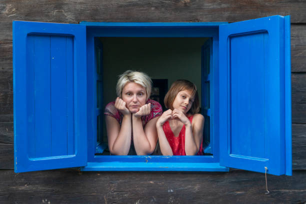 istock Mother and daughter  looking out the window 1194671719