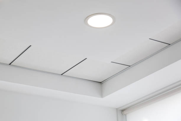 plafond multi-niveaux avec des protubérances tridimensionnelles et un plafond carrelé suspendu avec une lumière ronde intégrée. - plafond photos et images de collection