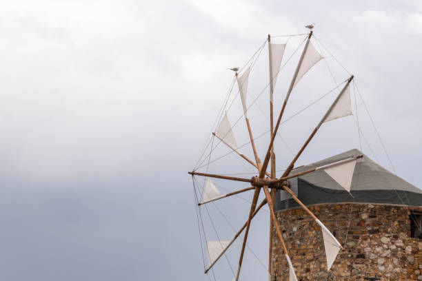 Detail of an old traditional windmill at the beach of Chios Town on Chios Island in Greece on a cloudy morning in spring, with light winds. Windmills have been used on Greek islands for grinding cereal grains for hundreds of years. These mills were originally built more than 100 years old and has been restored in recent years. For the mills to function, sails are mounted between the wooden spikes.