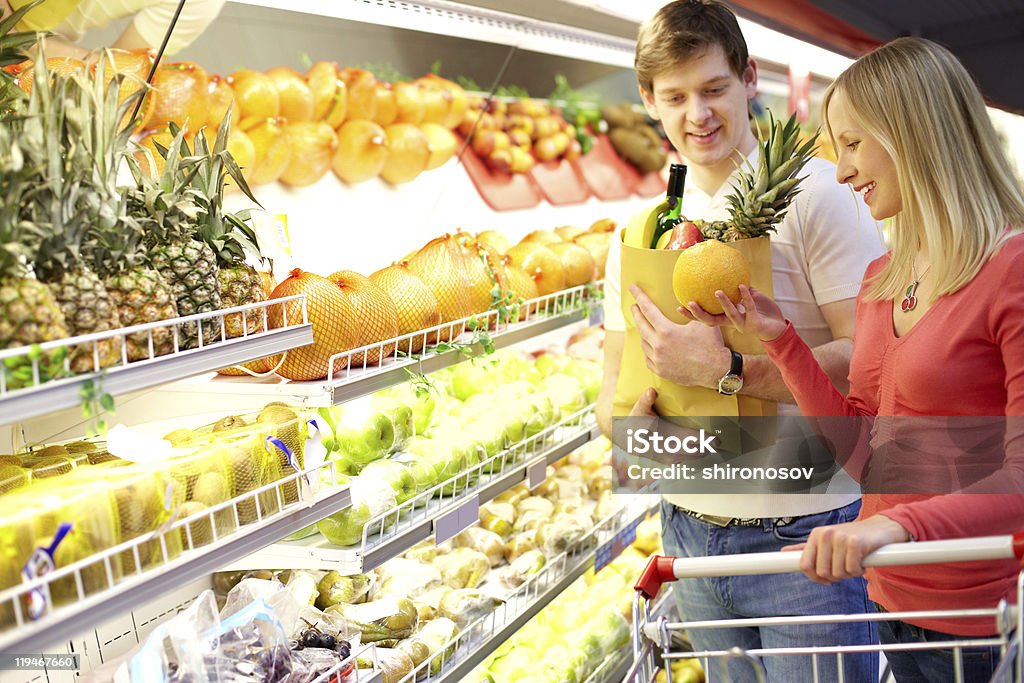 Man and woman shopping in the supermarket Portrait of couple choosing fruits in supermarket  Adult Stock Photo