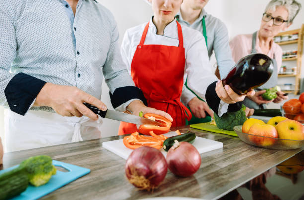 istock Man in training kitchen cutting vegetables under watchful eye of dietician 1194678384