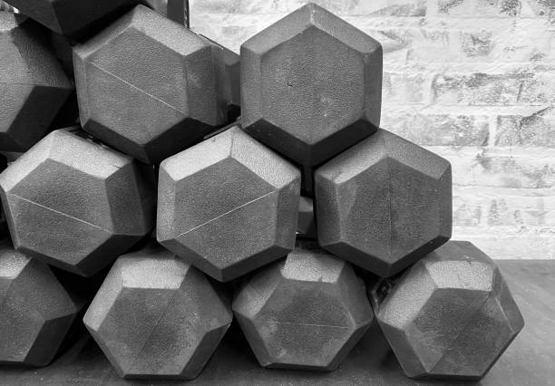 Black and white photo of free weight dumbbells stacked on gym floor with copy space