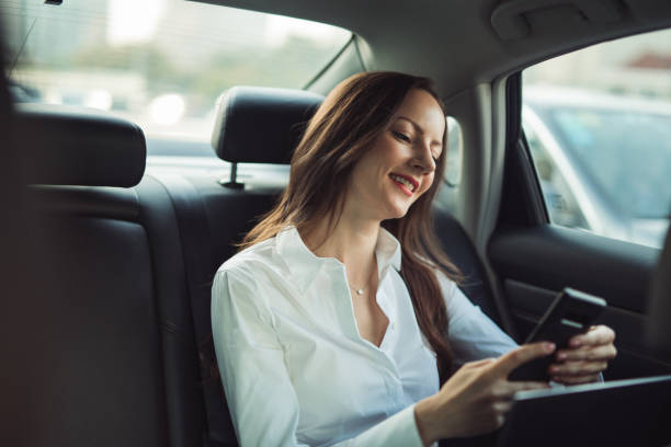 istock Business lady using mobile in backseat of a car 1194684331