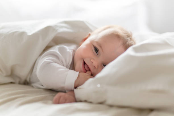 schattig gelukkig 7 maand baby meisje in luier liggend en spelen - baby stockfoto's en -beelden