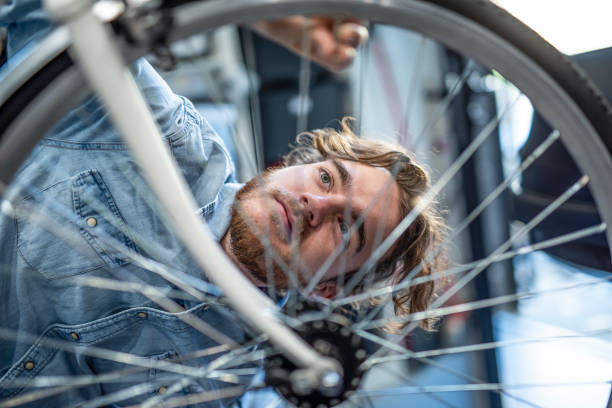 istock Bicycle mechanic examining a bent bicycle wheel. 1194692126
