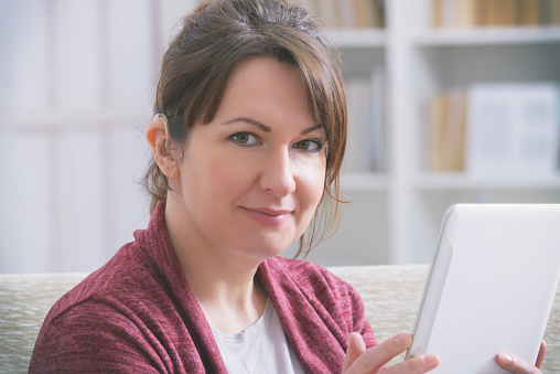 Deaf woman wearing hearing aid and using tablet