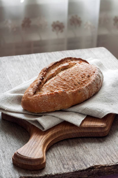 istock Loaf of whole wheat bread wooden board on kitchen table 1194694178
