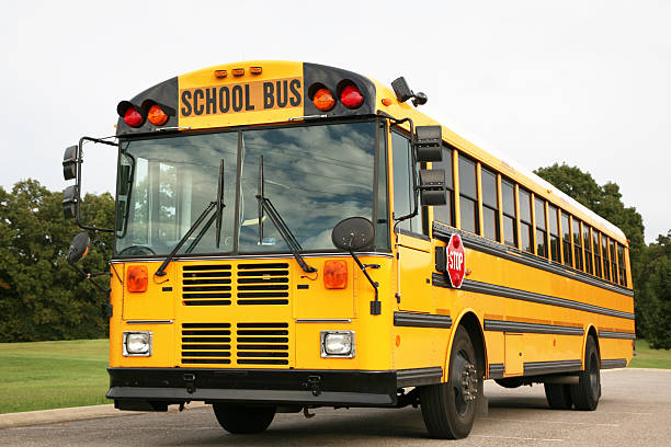 A bright yellow school bus ready to pick up school children stock photo