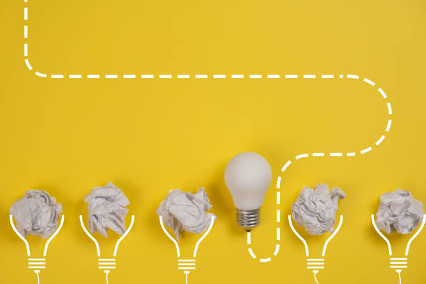 istock new idea concept with crumpled office paper and white light bulb on yellow background. Creative solution during brainstorming session concept. Flat lay, top view, copy space 1194697254