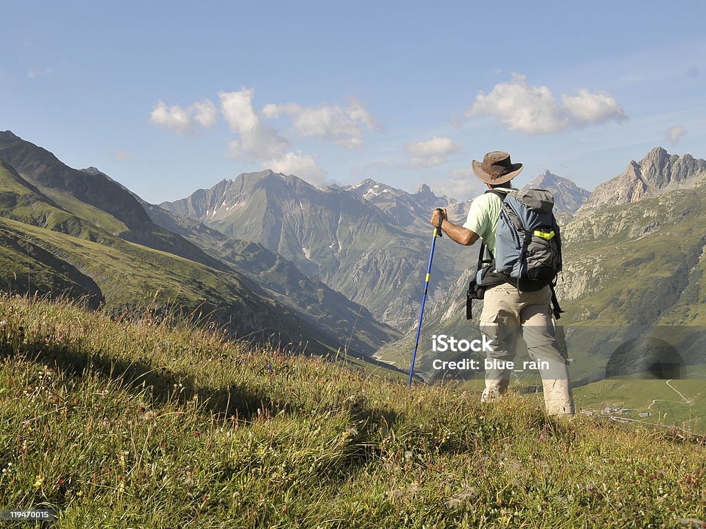 Hiking in Alps View of Alps mountains and a tourist standing on a footpath. Adult Stock Photo