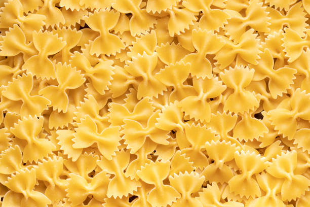 stos surowego makaronu włoskiego farfalle - bow tie pasta italian cuisine bow heap zdjęcia i obrazy z banku zdjęć