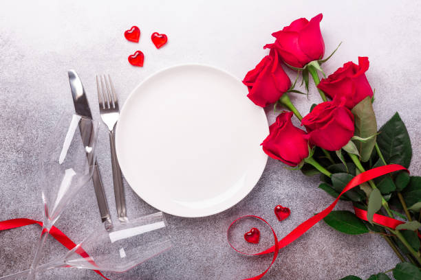 Valentines day table setting with bouquet of roses, red roses and champagne glasses on stone background. Top view. Valentine's greeting card stock photo