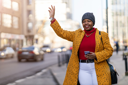 Woman waving for taxi on city street