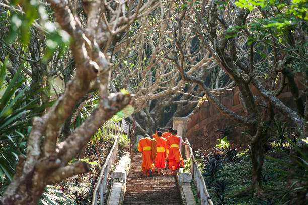 Tam Ting Caves near Ban Pak Ou, Mekong River, Laos - April 9, 2011: Tourists visiting the Tam Tim Caves on the Mekong River, Laos.  The caves are famous for their miniature Buddha sculptures. Hundreds of very small and some damaged wooden Buddhist figures are laid out over the wall shelves;
