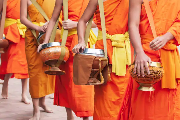 Close of Buddhist novice monks carrying their alms bowls for going on almsround in early morning. Luang Prabang, Laos. UNESCO the world heritage town.