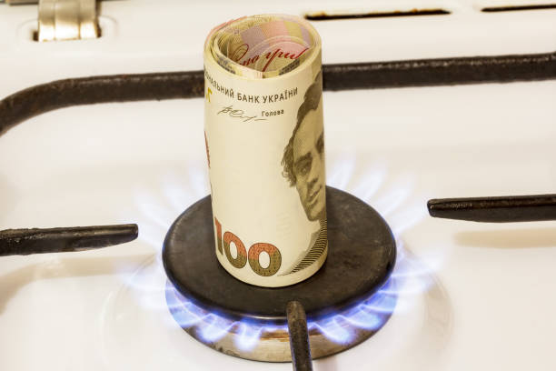 pila de cien notas de hryvnia en una estufa de gas en el centro de la comodidad del gas, quemaduras de gas. - ukraine hryvnia currency paper currency fotografías e imágenes de stock