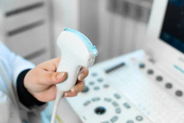 Photo of Doctor prepare an ultrasound machine for the diagnosis of a patient. Doctor puts media gel on an ultrasound transducer