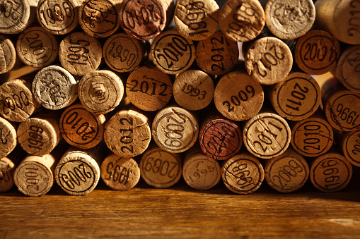 A collection of various vintages of wine corks arranged on a rustic wood background, copy space for custom text.