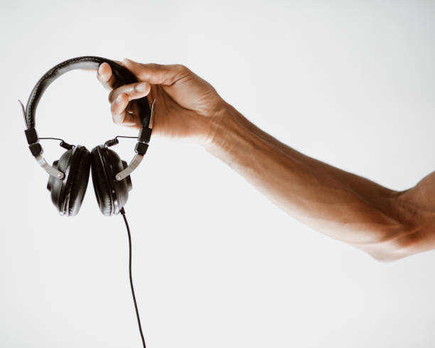 istock Hand holding a pair of headphones. 1194712281