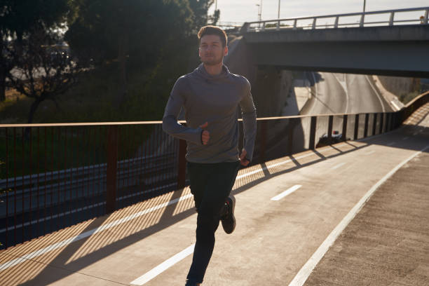 istock Young man running in athletic gear under a bridge 1194714784
