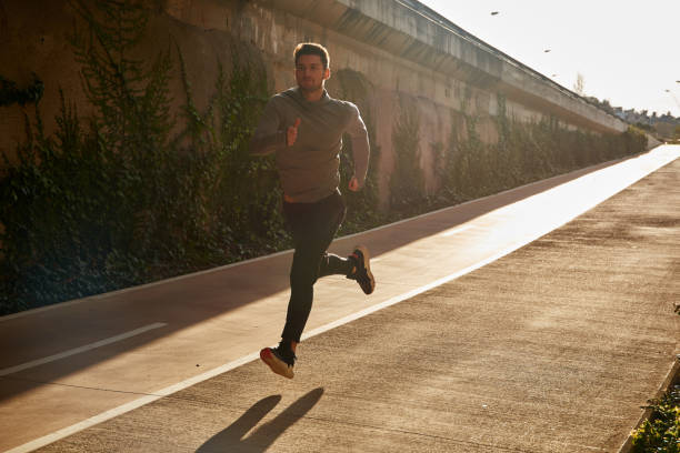 istock Man in athletic gear sprinting down a road 1194716522