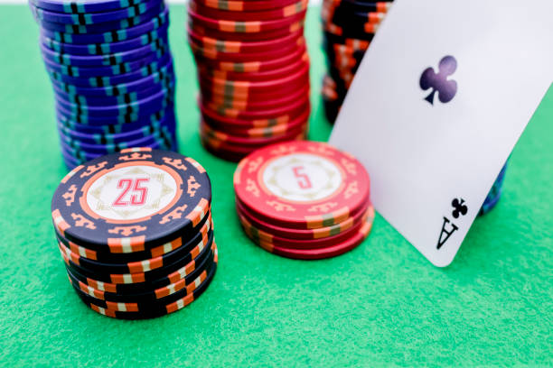 istock Stack of poker chips next to a card with an ace on a green game table 1194721680