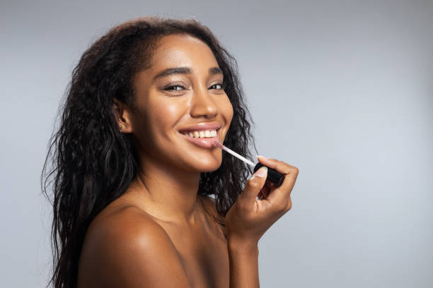 istock Happy lady applying lip gloss in studio 1194724838