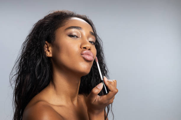 istock Amazing lady applying lip gloss in studio 1194724844