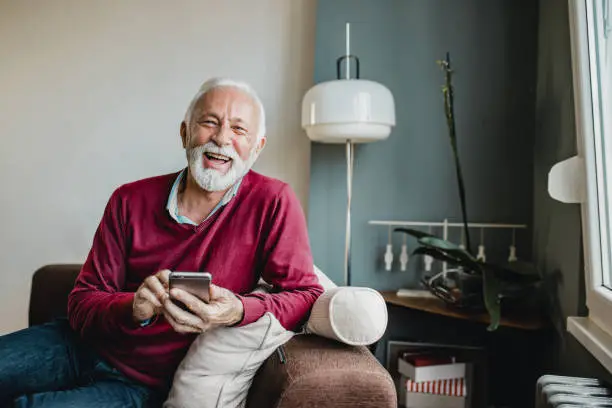 Photo of Portrait of senior men at home using smart phone