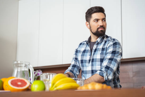 istock Handsome young man sitting at the kitchen table 1194732244
