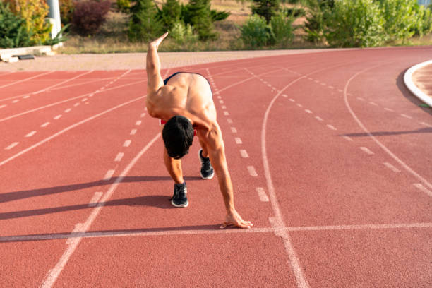 istock Runner using starting block to start his run on race track. Runner using starting block to start his run on running track in a stadium. Athlete starting his sprint on an all-weather running track. 1194736385