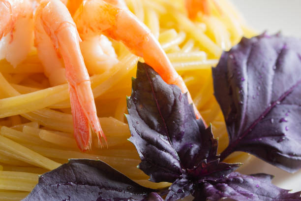 Spaghetti pasta with prawns and fresh purple basil branch close-up. Delicious seafood pasta