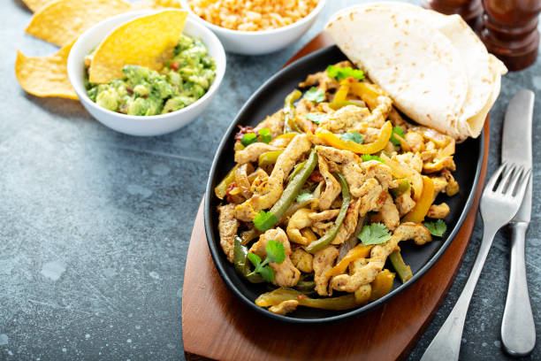 Chicken and bell peppers fajitas Chicken and bell peppers fajitas served in a cast iron pan with chips and guacamole mexican culture food mexican cuisine fajita stock pictures, royalty-free photos & images